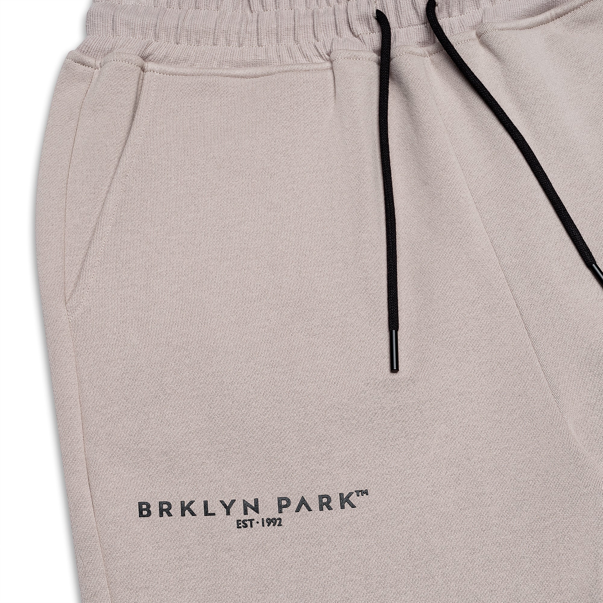 Close-up of Brklyn Park Essence Sweatpants waistband showing elastic, tonal logo print, and black drawstring