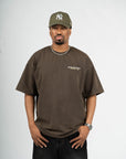 Male model wearing Brklyn Park oversized brown Members Only t-shirt styled with black jeans and new era NY yankees cap