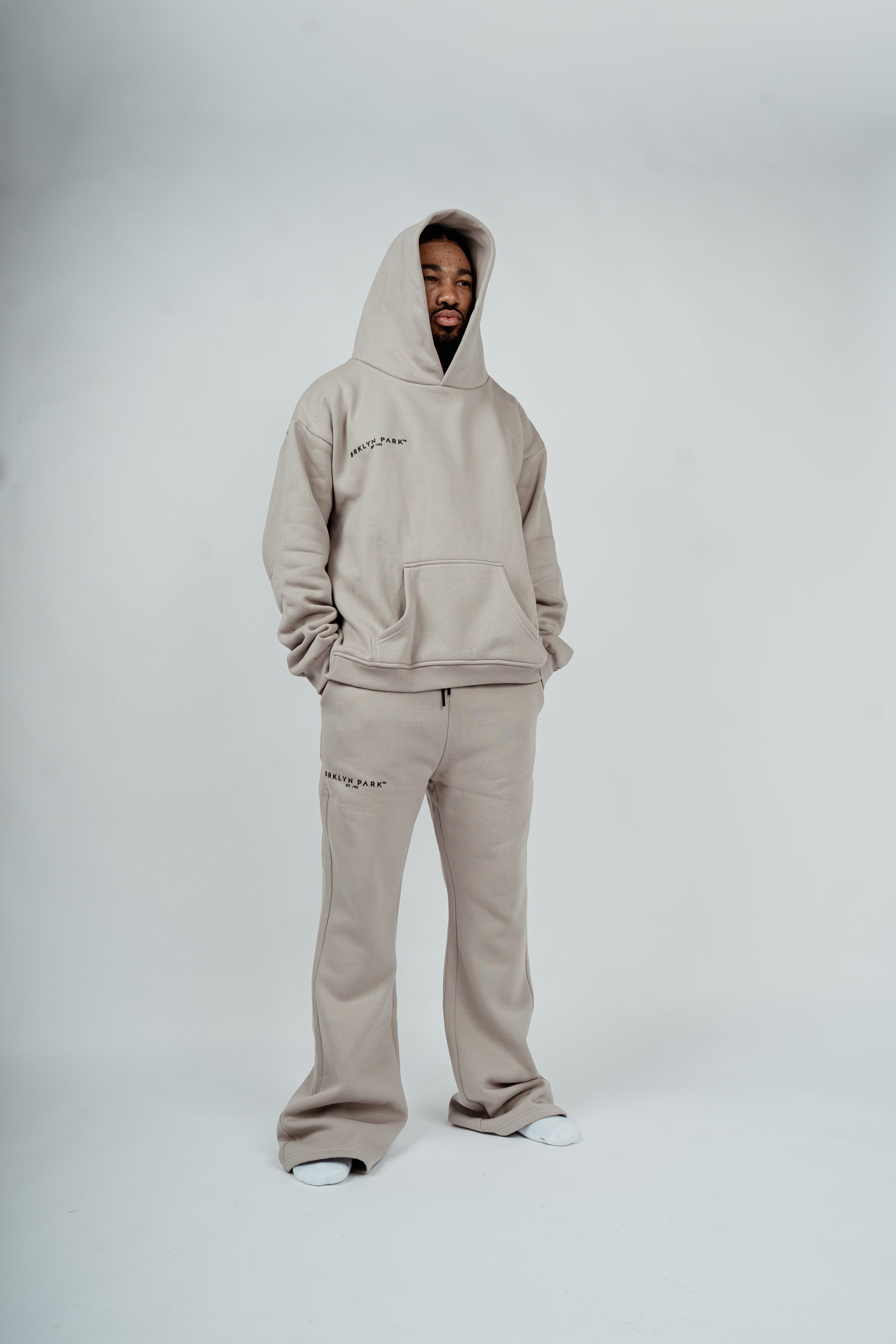 Male model wearing Brklyn Park gray fleece sweatpants with matching hoodie, styled for relaxed supreme streetwear look