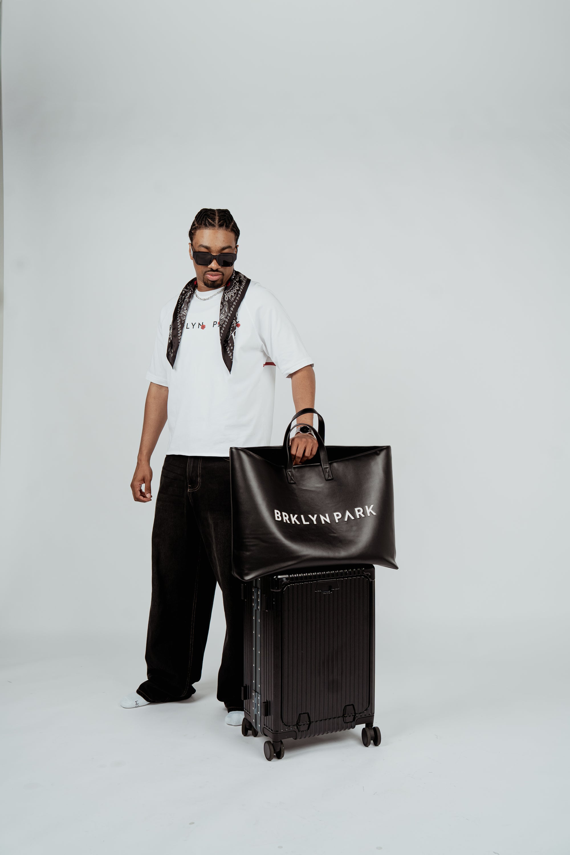 Model wearing the Brklyn Park Archangel Tee white oversized graphic t-shirt with angel artwork and red rose detailing, and leather tote black