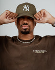 Brklyn Park Members Only brown t-shirt styled with chain necklace and green New York Yankees cap