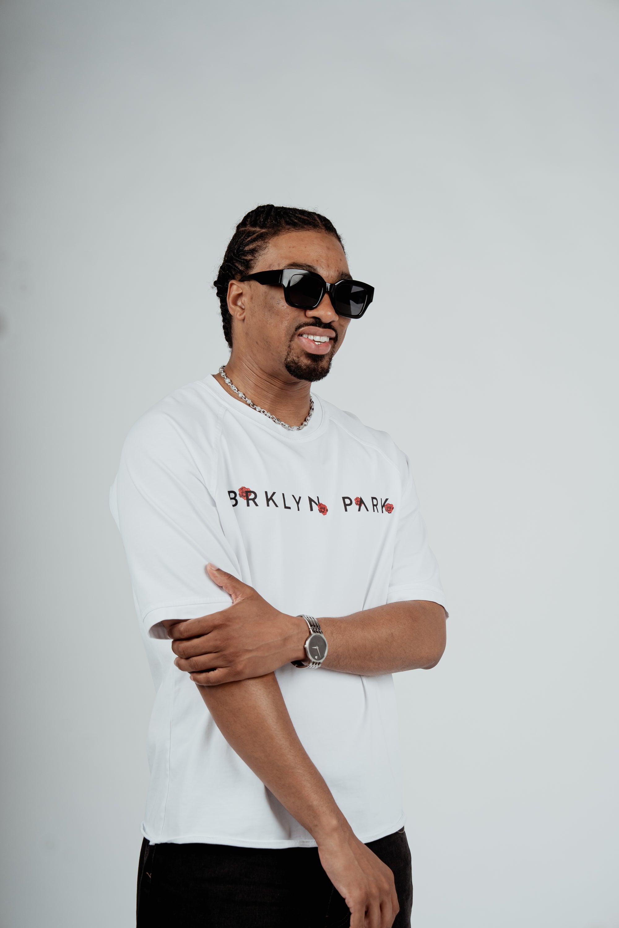 Model wearing the Brklyn Park Archangel Tee white oversized graphic t-shirt with angel artwork and red rose detailing,  supreme streetwear with black frame eyewear