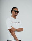 Model wearing the Brklyn Park Archangel Tee white oversized graphic t-shirt with angel artwork and red rose detailing, supreme streetwear with black frame eyewear