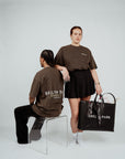 Two models wearing Brklyn Park brown oversized Members Only graphic t-shirts in minimalist studio setting
